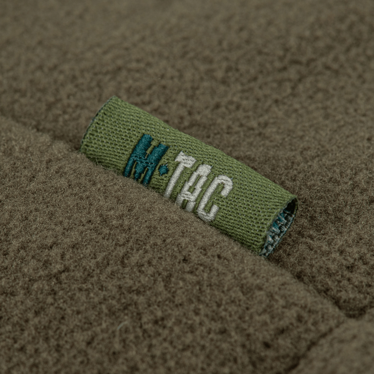 M-Tac Combat Fleece Polartec Jakke med fokuseret mærke på ærmet, viser detaljer af tekstur og brandlogo.