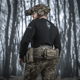 M-Tac Raglan Odin Mystery trøje med Odin-motiv, bæres af en person i taktisk udstyr i skovmiljø, fremhæver trøjens design og funktionalitet.