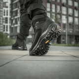 M-Tac Taktiske Demi-Season Støvler Pro Line med Vibram-sål til taktiske opgaver, visning af bund og greb i bymiljø.
