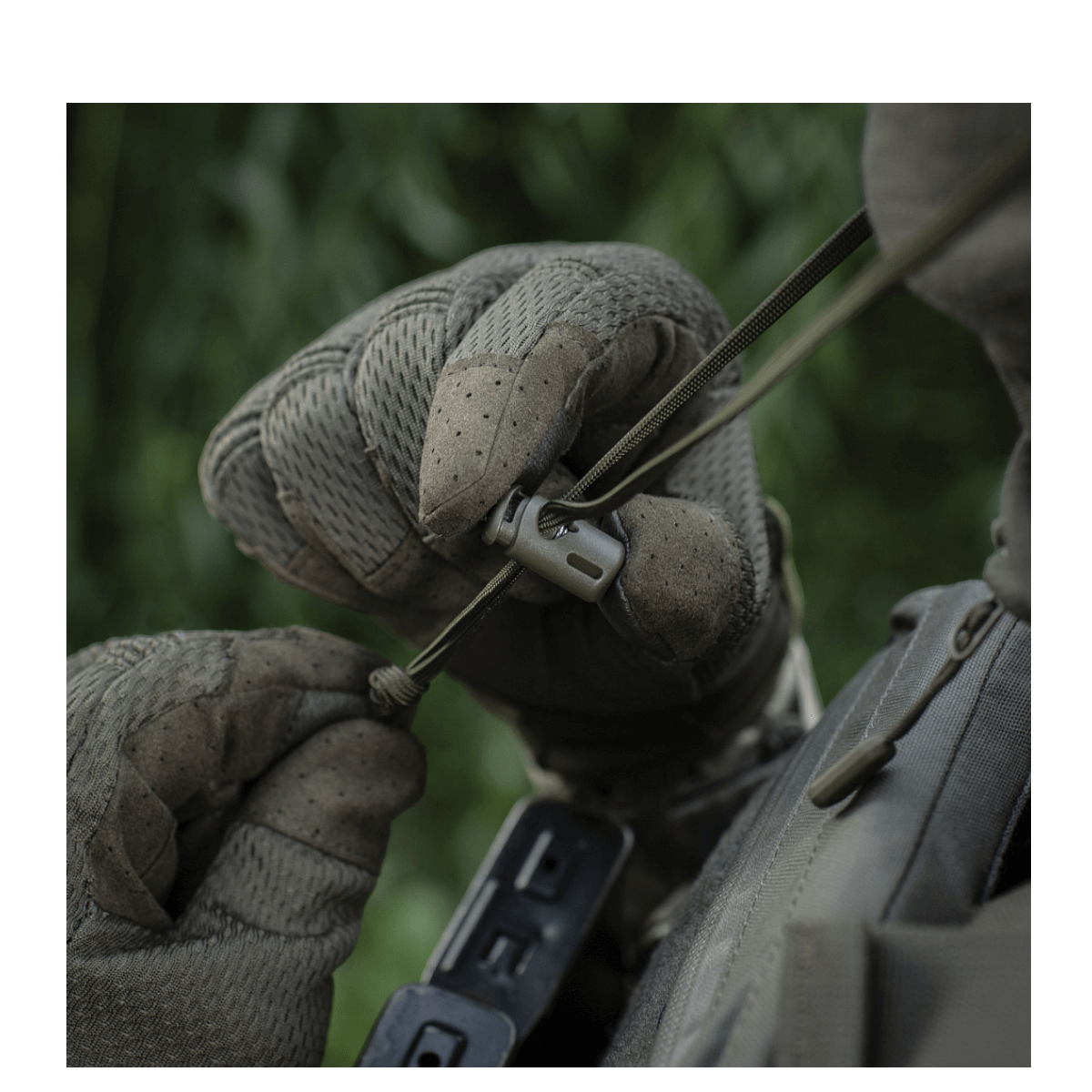 Person wearing tactical gloves adjusting equipment outdoors