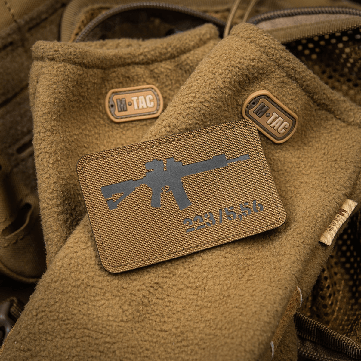 M-Tac AR-15 223/5,56 Laser Cut Patch fastgjort på brun taktik tæppe med M-Tac logoer, designet til udendørs og militærbrug.