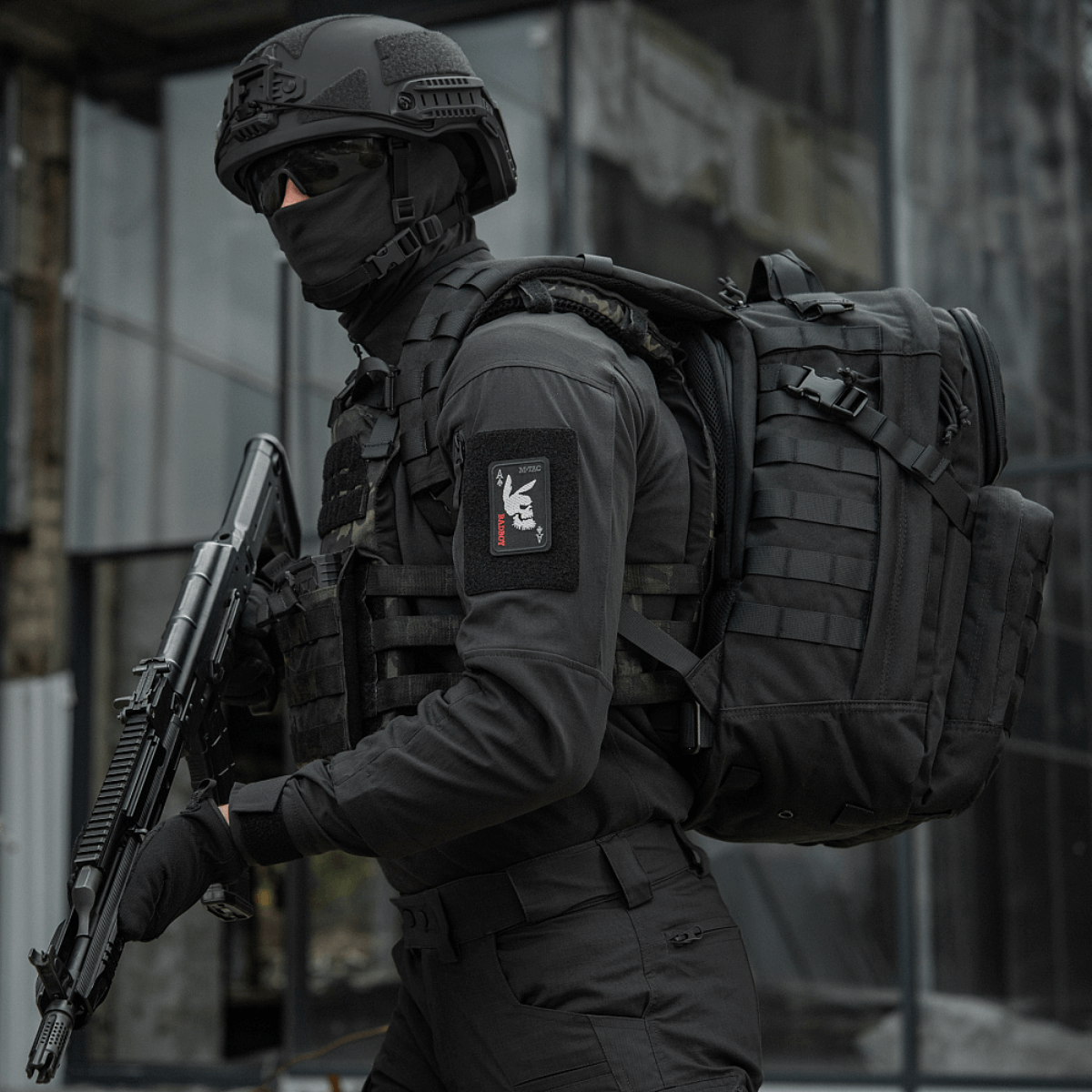 Taktisk operatør iført "M-Tac Patch Bad Boy (Broderi)" med kaninkranium på ace of spades kort, holdende våben, i urban indstilling.