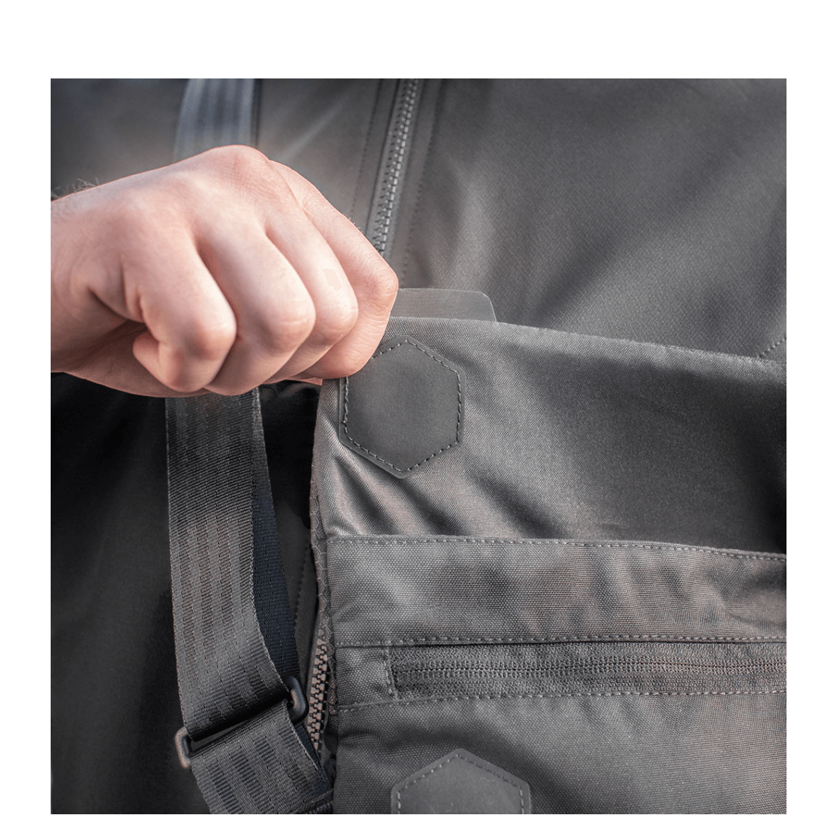 Hånd åbner lomme på M-Tac Konvert Taske Elite fremstillet af holdbart Cordura-materiale med magnetisk ventilåbning.