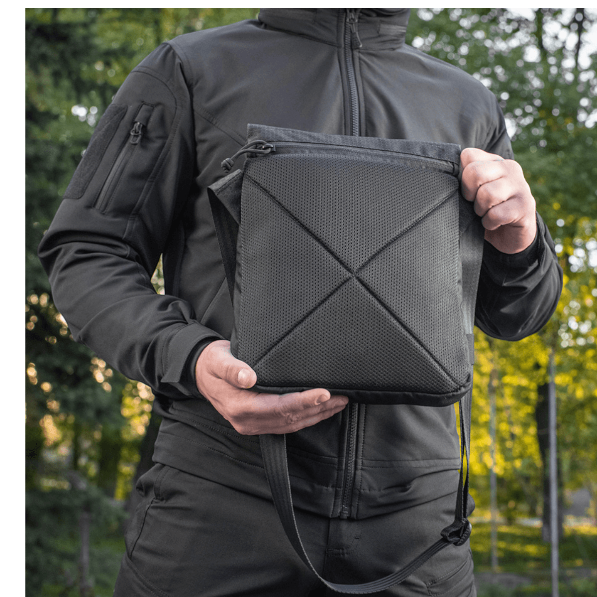 M-Tac Konvert Taske Elite i Cordura 500D og Hex 1000D, med tablet-design og justerbar skulderrem, holdt af person i naturen.