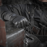 En person iført M-Tac Handsker Police Gen.2 i taktisk situation, med skridsikker greb og justerbar Velcro, designet til politi og sikkerhedsarbejde.