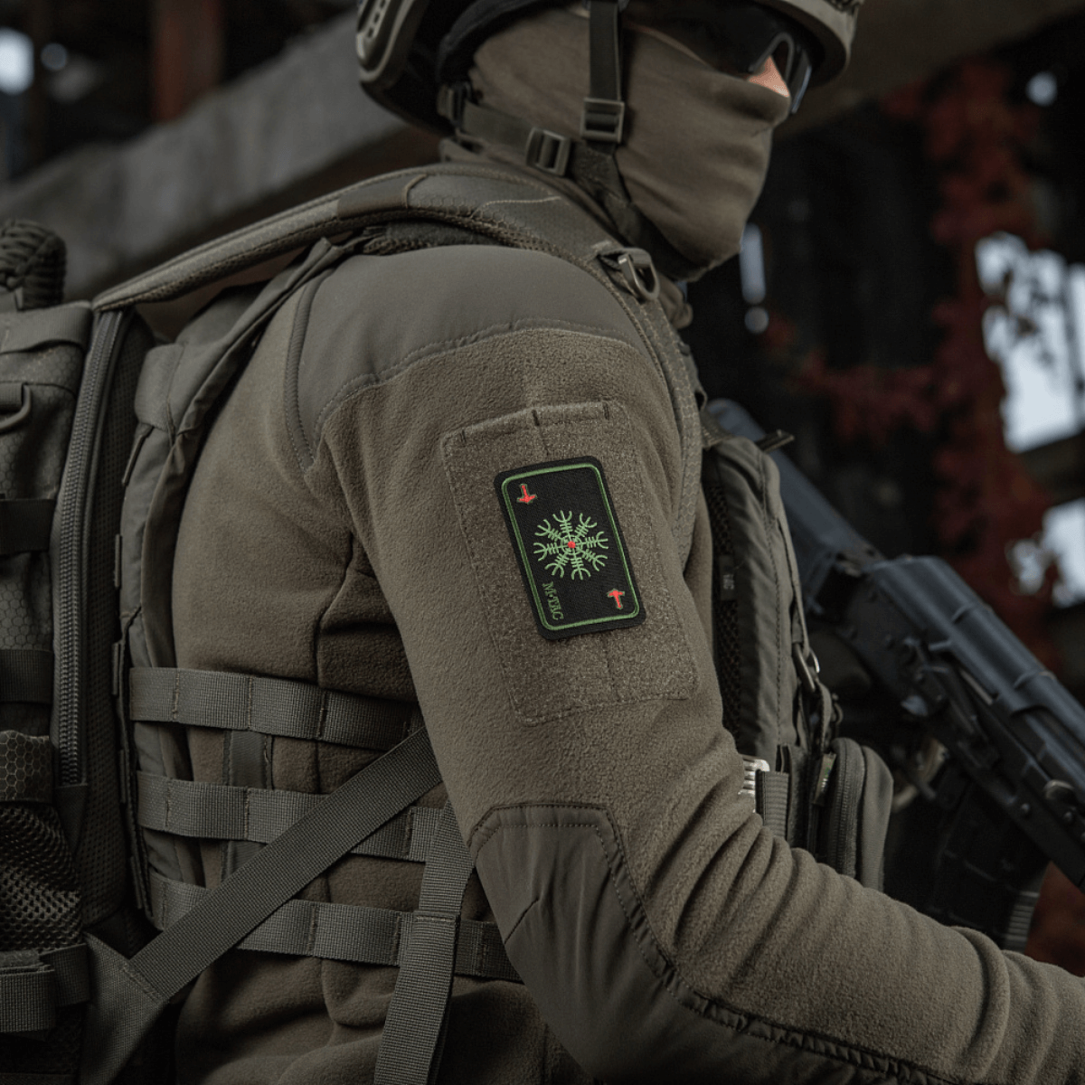 Soldat med M-Tac Patch Kort Helm of Horror (Broderi) fastgjort til jakke, broderet med ægishjálmur symbol, Cordura 500D materiale.