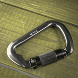 M-Tac Key-Lock Karabinhage i aluminium på træoverflade, ideel til klatring og sikkerhed, CE EN362 certificeret, ergonomisk design.