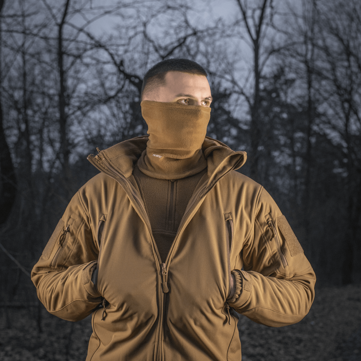 Mand iført M-Tac Tube Scarf Polartec i skov, perfekt til udendørs aktiviteter og koldt vejr.